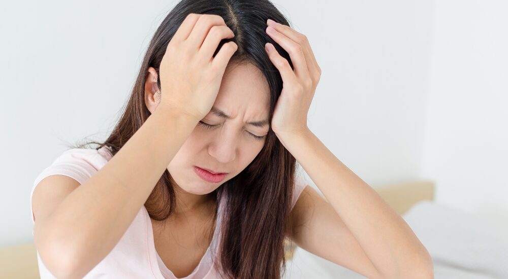 頭を抱え込み、強いストレスや【自律神経】の乱れによる深刻な不調に悩まされている状況です。どうにもならない慢性的な頭痛やイライラ感で、心身ともに余裕がなくひどく辛そうな感情を表現しています。
